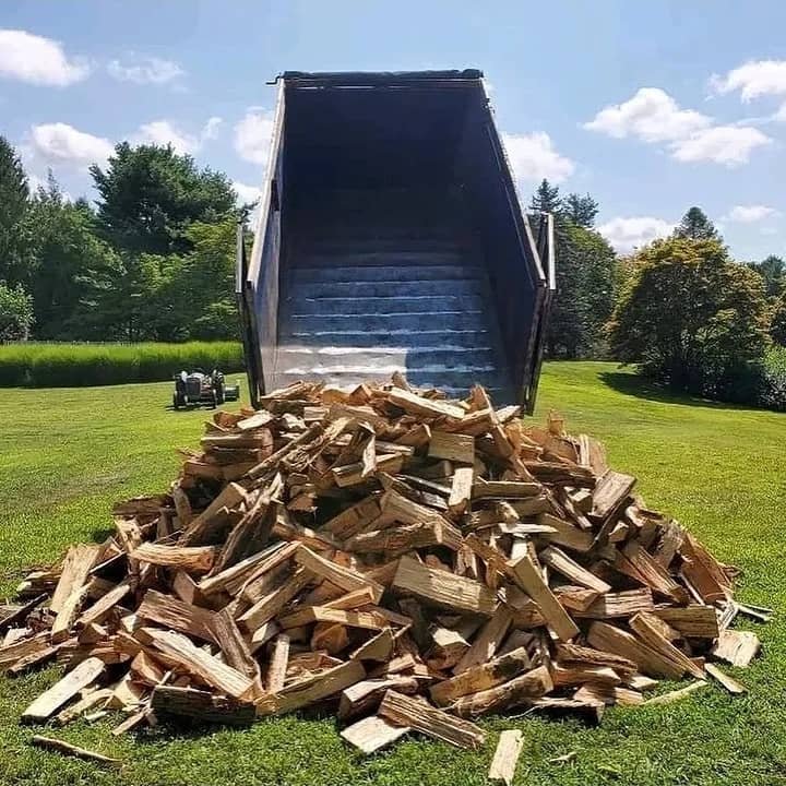 A fresh load of split firewood tipped onto a customer's lawn